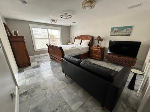 a bedroom with a bed and a couch and a television at Stylish Bungalow Near Dining, Parks & Entertainment in Jacksonville