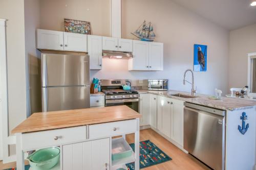 a kitchen with white cabinets and a stainless steel refrigerator at Ocean View & Whale Watching! Spouting Horn Three in Depoe Bay