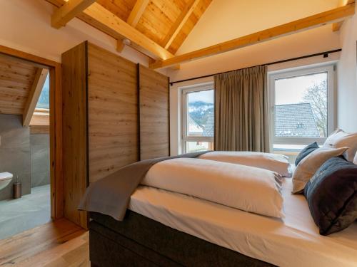 two beds in a bedroom with wooden walls and windows at Mountain Chalet Luxx in Sankt Lorenzen ob Murau