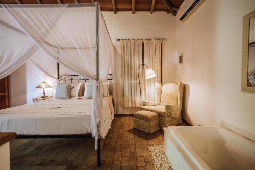 a bedroom with a bed and a chair and a tub at Pousada Terra Madre in Ilhabela