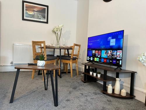 a living room with a television and a dining table at Spacious Detached Home Close to City with Ample Parking on the Drive in Derby