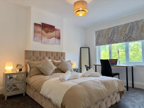 a bedroom with a bed and a desk and windows at Spacious Detached Home Close to City with Ample Parking on the Drive in Derby
