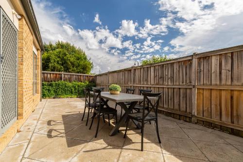un patio con mesa y sillas en una valla en VAQUAY Provence In South Morang, en South Morang 