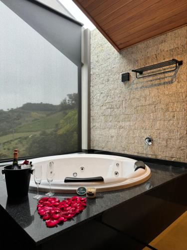 a bath tub with wine glasses and a window at CABANAS LE VIGNE in Pinto Bandeira