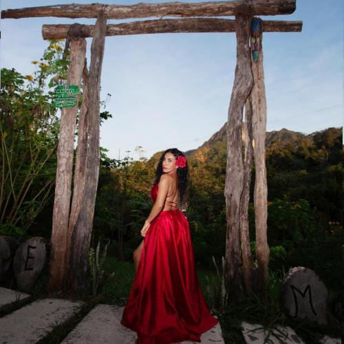 a woman in a red dress standing under a wooden arch at Mirador Jungle El Macuti in Rurrenabaque