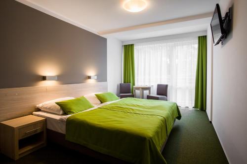 Habitación de hotel con cama verde y ventana en Hotel *** NAT Krynica Morska en Krynica Morska