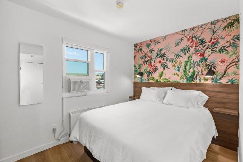 a bedroom with a white bed with a floral wallpaper at Uptown Inn by Vantaggio Suites in San Diego