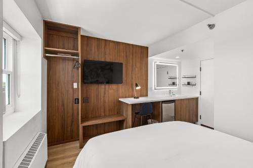 Uptown Inn by Vantaggio Suites في سان دييغو: غرفة نوم بسرير ومكتب ومغسلة