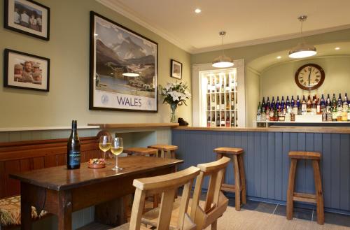 a bar with a wooden table and some wine glasses at Y Meirionnydd Boutique Hotel in Dolgellau