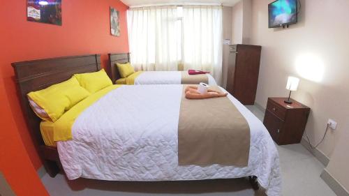 a bedroom with two beds with yellow pillows at Hostal Flor de los Ángeles Guamote in Guamote