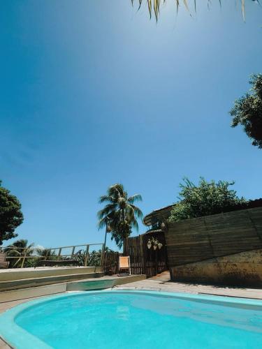 a blue swimming pool with a fence and palm trees at Pousada Sossego in Pipa