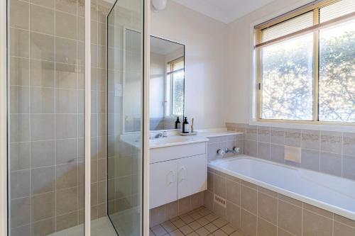 Un baño con ducha, bañera y lavabo. en Waterside Retreat, en Sussex Inlet