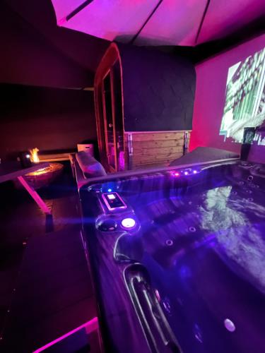- une piscine dans une chambre avec des lumières violettes dans l'établissement Maison spa sauna, à Morangis