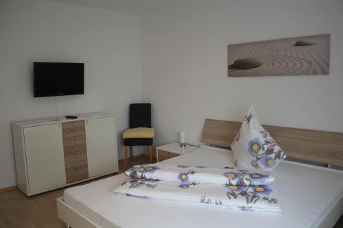 Schlafzimmer mit einem weißen Bett und einem TV an der Wand in der Unterkunft Appartements-Steinkirchner in Straubing