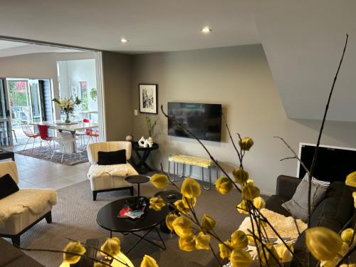 a living room filled with furniture and a flat screen tv at Peppertree lodge in Havelock North