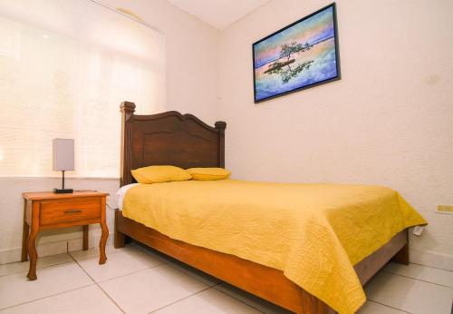 a bedroom with a bed with a yellow bedspread on it at Ocean Pearl Boutique Hotel in Roatan