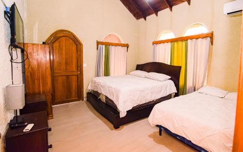 a bedroom with two beds and a tv and a door at Ocean Pearl Boutique Hotel in Roatan
