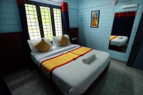 Un dormitorio con una cama grande con almohadas amarillas y blancas en NARMADA HOMESTAY Yamuna, en Malappuram