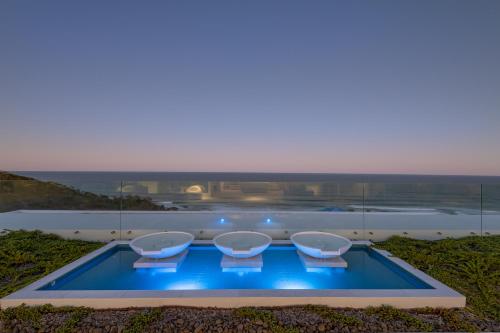 a swimming pool with four chairs and a view of the ocean at Azure in Sunshine Beach
