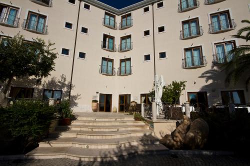 a large white building with stairs in front of it at Hotel Brancamaria in Cala Gonone