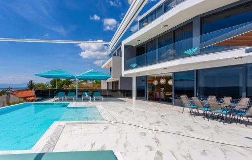 a building with a swimming pool and chairs and umbrellas at Gorgeous Home In Crikvenica With Sauna in Crikvenica