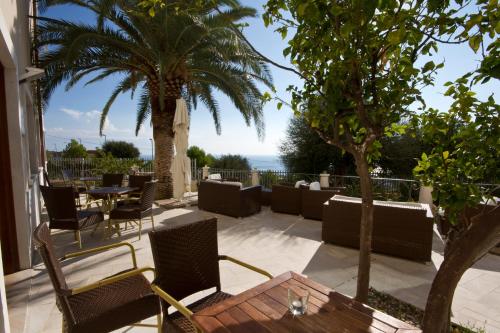 a patio with chairs and a table and palm trees at Hotel Brancamaria in Cala Gonone