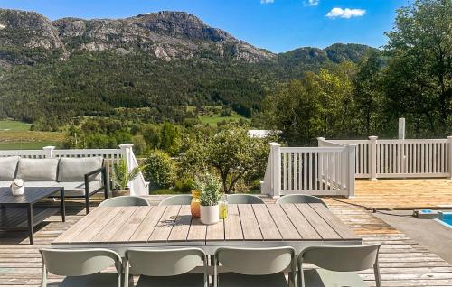 a wooden table and chairs on a deck with mountains at 3 Bedroom Stunning Home In Vikebygd in Vikebygd