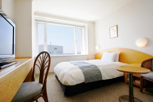a hotel room with a bed and a window at Hotel Kyocera in Kirishima