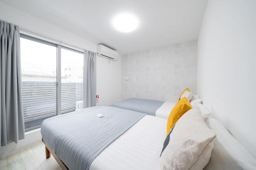 a white bedroom with a bed and a large window at Family Home Petit Denpo 101 in Osaka