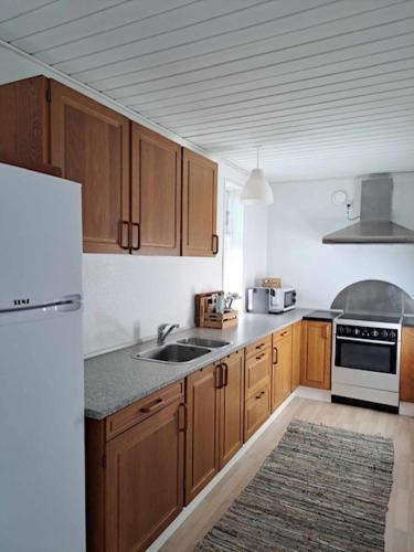 a kitchen with wooden cabinets and a white refrigerator at Hyggelig ferielejlighed ved Givskud in Give