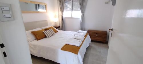 Schlafzimmer mit einem Bett mit weißer Bettwäsche und Kissen in der Unterkunft Departamento Amplio en Corrientes Capital in Corrientes