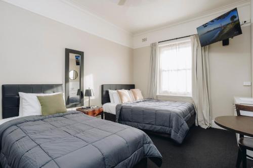 a hotel room with two beds and a tv at Hotel Gosford in Gosford