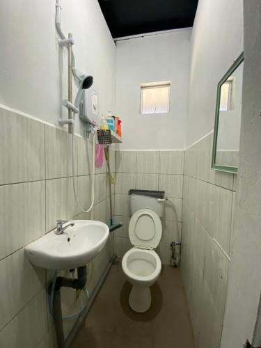 La salle de bains est pourvue de toilettes et d'un lavabo. dans l'établissement Julian Homestay, à Tuaran