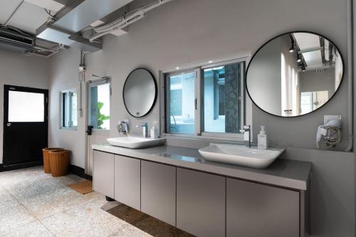 a bathroom with two sinks and two mirrors at 1954 Guest House in Taipei
