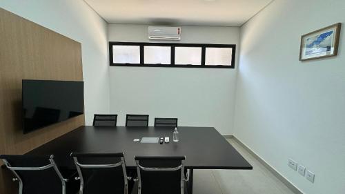 a conference room with a black table and chairs at Monte Carmel in Ribeirão Preto