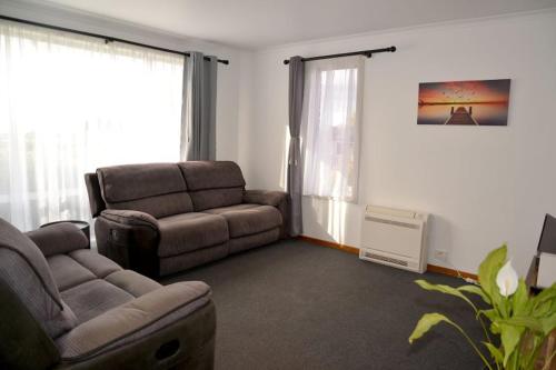 a living room with a couch and a chair at The Cozy Penguin with Sea Views in Cooee
