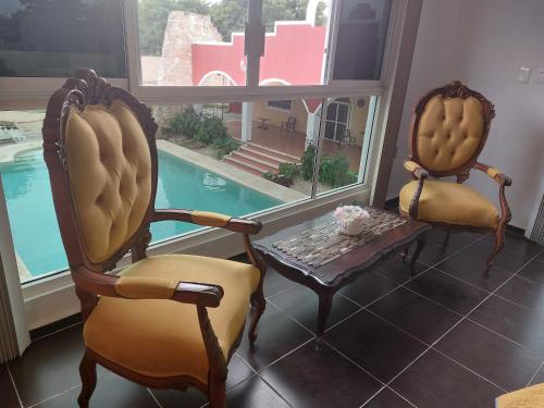 two chairs and a table in a room with a pool at Quinta Eva and Ivan in Kanasín