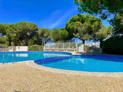 une piscine bleue avec des arbres en arrière-plan dans l'établissement Studio avec piscine, parking et terrasse à Port Camargue - FR-1-307-262, au Grau-du-Roi