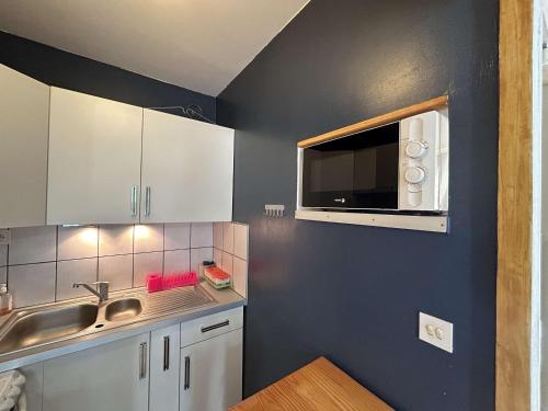 une cuisine avec un évier et un micro-ondes dans l'établissement T2 avec loggia, proche mer et Seaquarium, 5 couchages, ménage inclus - FR-1-250-274, au Grau-du-Roi
