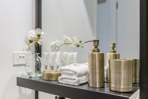 a shelf with gold and white towels and a mirror at VAQUAY Soho In Docklands in Melbourne