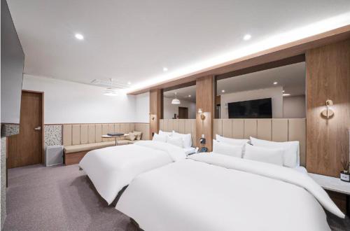 a bedroom with four white beds in it at Brown Dot Hotel Andong Ok-dong in Andong