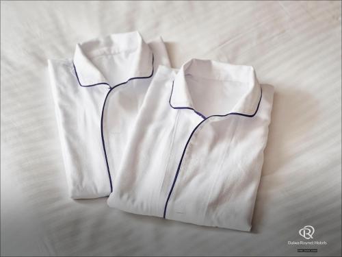a white shirt laying on top of a bed at Daiwa Roynet Hotel Chiba Ekimae in Chiba