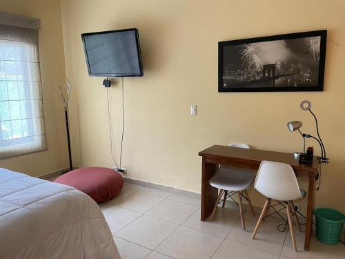 a bedroom with a desk and a television on the wall at Urban Oasis in Mexico City