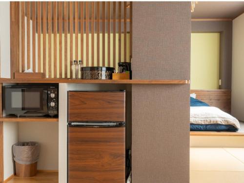 a kitchen with a refrigerator and a bed in a room at Nozawa Onsen Azegamikan in Nozawa Onsen