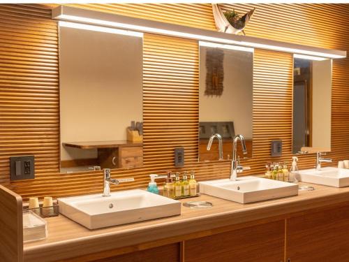 a bathroom with two sinks and a large mirror at Nozawa Onsen Azegamikan in Nozawa Onsen