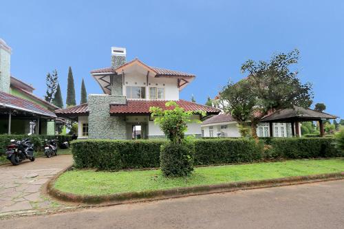 a house on a street with bushes and trees at Villa ChavaMinerva Aries Ciater with Private Pool in Subang
