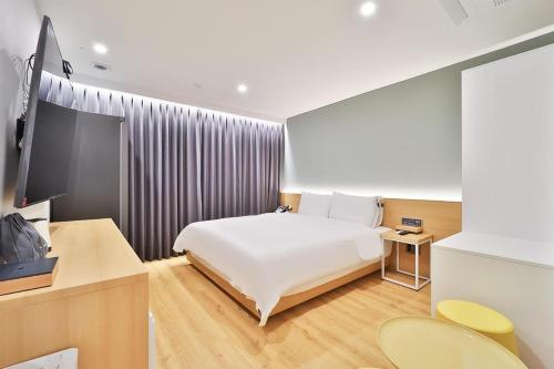 a hotel room with a bed and a television at Gongdam Stay Hotel Ulsan Samsan in Ulsan