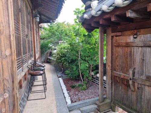 a patio with a wooden fence and chairs in a garden at Sarangroo in Jeonju
