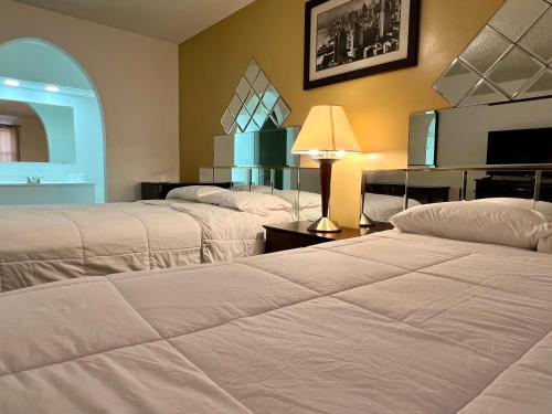 a hotel room with two beds and a mirror at Royal Inn - Neptune in Neptune City