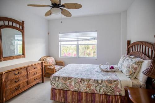 Un dormitorio con una cama y una cómoda y una ventana. en GRACEBAY TOWNHOMES B3, 5 minutes walk to gracebay beach, en Long Bay Hills